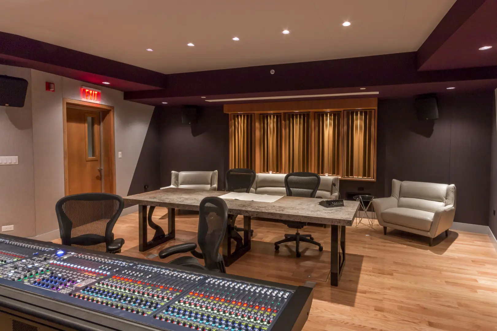 A modern recording studio featuring a mixing console, sleek furniture, and soundproofing, with warm lighting and wooden floors A modern recording studio featuring a mixing console, sleek furniture, and soundproofing, with warm lighting and wooden floors